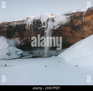 Der wunderschöne Seljalandsfoss in Island ist im Winter mit Schnee bedeckt. Stockfoto