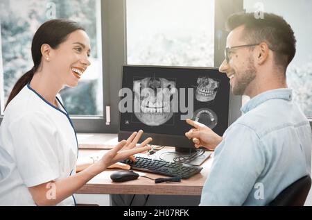 Zahnarzt und Patient wählen Behandlung in einer Konsultation mit modernen 3D-Röntgenbild auf dem Bildschirm Stockfoto
