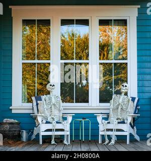 Skelette sitzen auf Stühlen auf der Veranda für halloween Stockfoto