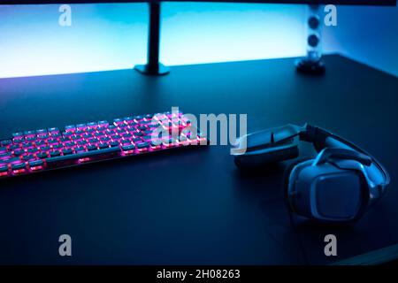 Gaming-Zubehör auf dunklem Tisch. Tastatur mit Hintergrundbeleuchtung und Stereo-Kopfhörern. Professionelle Computerspiel spielen, esport Business und online wo Stockfoto