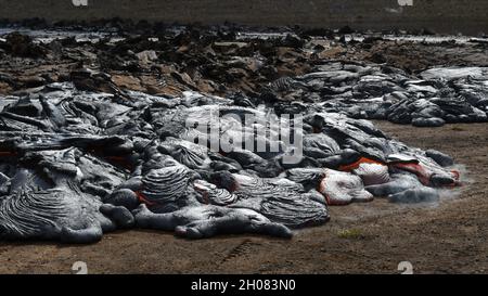 Pahoehoe Lavafluss am Fagradalsfjall, Island. Lavakruste ist grau und schwarz, geschmolzene Lava ist rot und orange. Dampf und Gas sind sichtbar. Stockfoto