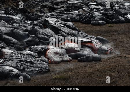 Pahoehoe Lavafluss am Fagradalsfjall, Island. Lavakruste ist grau und schwarz, geschmolzene Lava ist rot und orange. Dampf und Gas sind sichtbar. Stockfoto