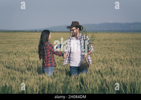 Zwei Bauern, Mann und Frau, schüttelten sich im Sommer vor der Ernte im Gerstenfeld die Hände Stockfoto