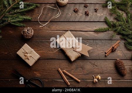 Draufsicht Weihnachtshintergrund mit Holztisch und rustikalen Geschenken in Bastelpapier verpackt, Kopierraum Stockfoto