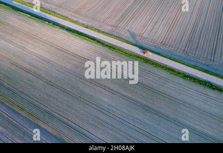 Luftbild des Traktors mit Heutedderausrüstung, die auf unbefestigten Straßen fährt, schießen von der Drohne Stockfoto
