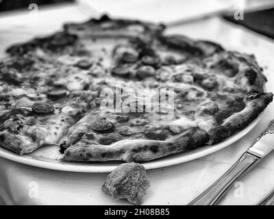 Graustufen-Schuss einer ganzen leckeren Pepperoni-Pizza Stockfoto