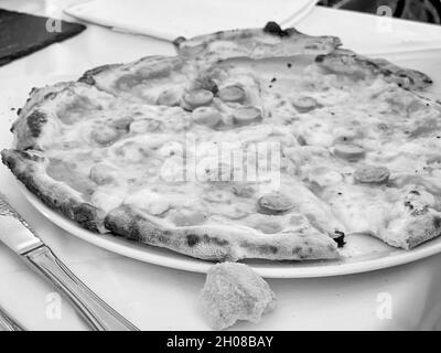 Graustufen-Schuss einer ganzen leckeren Pepperoni-Pizza Stockfoto