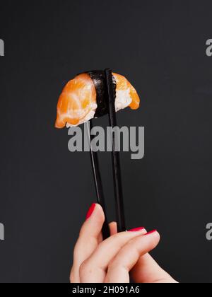 Frau mit zwei Essstäbchen und Lachs-Sushi. Auflösung und hochwertige schöne Fotos Stockfoto
