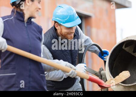 Bauherrin schaufelt Sand in den Zementmischer Stockfoto