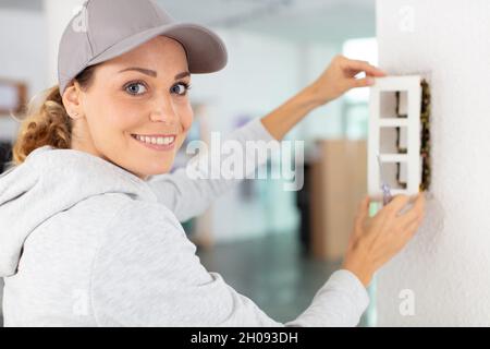 Frau mit repariert eine Steckdose Stockfoto