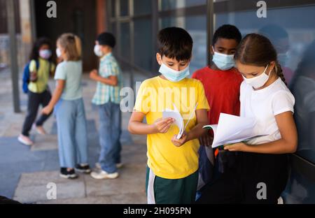 Schulkinder in Masken reden draußen Stockfoto