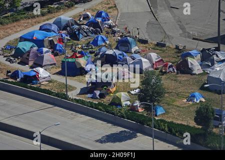 Ein Obdachlosenlager, bestehend aus Zelten und Planen, wird tagsüber aus einer erhöhten Sicht in einer Stadt gezeigt. Stockfoto