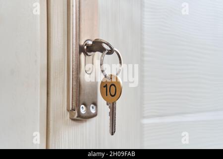 Ein Schlüssel mit Schlüsselanhänger im Schlüsselloch der Tür. Kaufen Sie ein neues Home-Konzept. Immobilienmarkt. Stockfoto