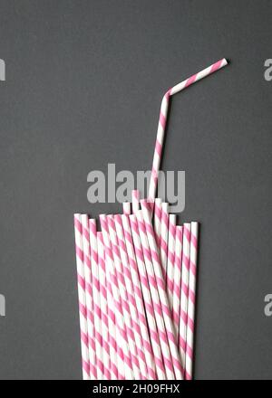 Glasform mit Stroh aus Papierhalmen auf schwarzem Hintergrund. Party oder kein Plastikkonzept. Stockfoto