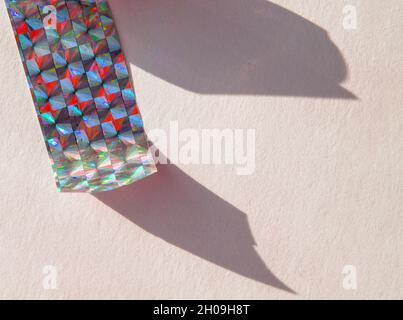 Ein Stück holographische Folie auf weißem Hintergrund, harte Schatten von der Folie. Draufsicht. Zu kopierende Position. Stockfoto