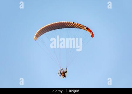 Angetriebener Paragliding-Flug gegen den blauen Himmel. Stockfoto