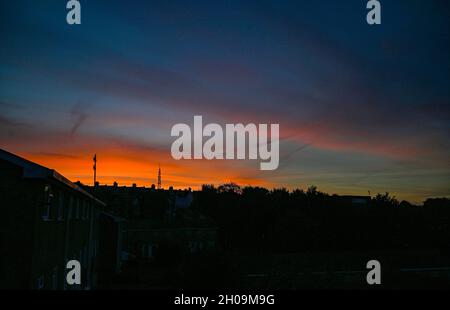 Brighton UK 12. Oktober 2021 - Ein wunderschöner Sonnenaufgang über den Dächern von Brighton und der Whitehawk Hill Sendestation, während der trockene warme Zauber des Wetters im Südosten andauert : Credit Simon Dack / Alamy Live News Stockfoto