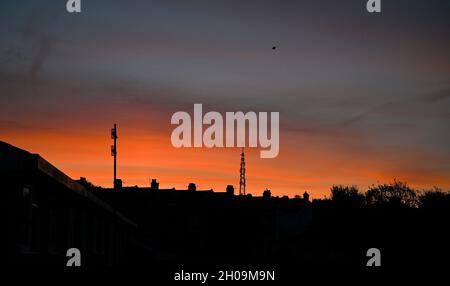 Brighton UK 12. Oktober 2021 - Ein wunderschöner Sonnenaufgang über den Dächern von Brighton und der Whitehawk Hill Sendestation, während der trockene warme Zauber des Wetters im Südosten andauert : Credit Simon Dack / Alamy Live News Stockfoto