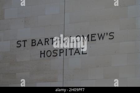 Der Name des St. Bartholomäus Krankenhauses ist an der Wand am Haupteingang des Krankenhauses angebracht. London, England, Großbritannien. Stockfoto