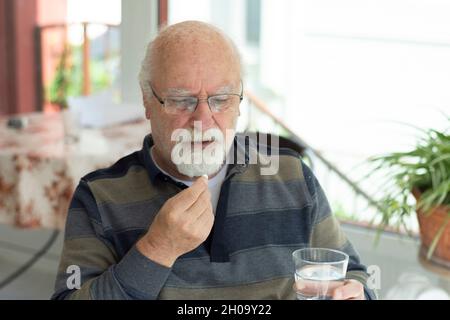 Kahler alter Mann mit Brille, der seine täglichen Medikamente nimmt. Selektiver Fokusmann Stockfoto