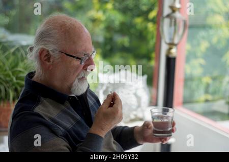 Kahler alter Mann mit Brille, der seine täglichen Medikamente nimmt. Selektiver Fokusmann Stockfoto