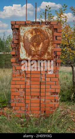 Altes rostetes Stahltor mit sowjetischem Wappen, UdSSR-Emblem. Verlassene Militärstadt Irbene in Lettland. Stockfoto