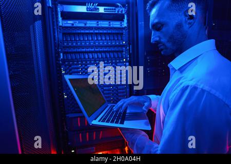 Serveringenieur mit Laptop, der an Datensicherheitsproblemen arbeitet Stockfoto