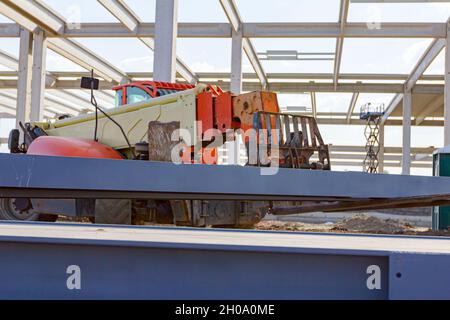 Teleskopstapler, der bis zu seinem Transport Stapel von lackierten, geschweißten Metallträgern, Struktur Träger für Metallbau auf der Baustelle. Stockfoto