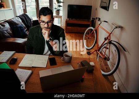 Gemischter Geschäftsmann, der von zu Hause aus am Laptop arbeitet, während er zu Hause sitzt Stockfoto