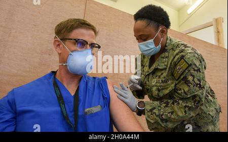 AGANA HEIGHTS, Guam (Jan 4, 2021) – Hospital Corpsman 2nd Class Vivian Hyde, dem US Naval Hospital Guam (USNH Guam) zugewiesen, verabreicht LT. Cmdr. Einen COVID-19-Impfstoff. Lawrence L. William Jr., ein Chirurg, der dem USNH Guam zugewiesen wurde. Das US-Verteidigungsministerium hat bei seiner ersten Lieferung eine begrenzte Menge an COVID-19-Impfdosen erhalten und verabreicht den Impfstoff derzeit an Mitarbeiter der Phase 1a, darunter Gesundheitsdienstleister und Support-Mitarbeiter, Rettungsdienste und Mitarbeiter der öffentlichen Sicherheit. Stockfoto