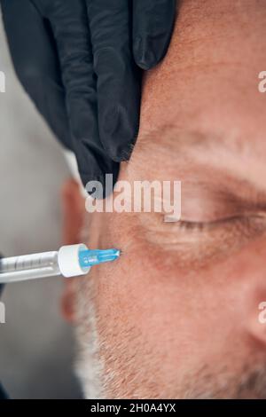 Arzt Kosmetikerin Hände machen Injektion in das Gesicht des Mannes Stockfoto