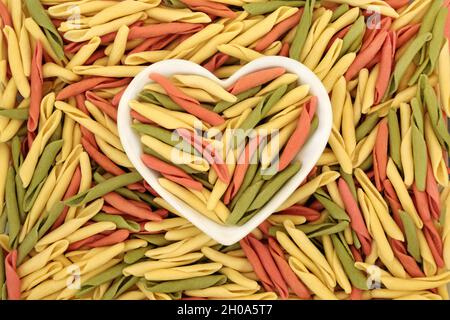 Fusilli pulgiesie Italienische Pasta in einer herzförmigen Schüssel. Kreatives Konzept für gesunde Ernährung. Abstrakter Hintergrund, Draufsicht, flach liegend. Stockfoto