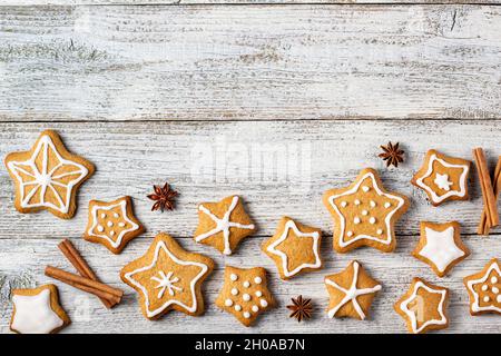 Rand von weihnachtlichen Lebkuchen in Sternform mit Glasur- und Gewürzmustern auf weißem Holzhintergrund. Draufsicht mit Kopierbereich Stockfoto