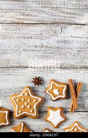 Rand von weihnachtlichen Lebkuchen in Sternform mit Glasur- und Gewürzmustern auf weißem Holzhintergrund. Draufsicht mit Kopierbereich Stockfoto