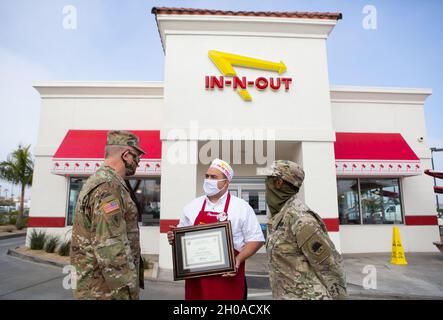 Kaplan der US-Armee (Col.) Russell Dewell, links, der als Staatskaplan der California National Guard fungiert, und California State Guard Chaplain (Maj.) Brenda ThreatT, rechts, übergibt Benjamin Corona, einem in-N-Out Store Manager, am 8. Januar 2021 in Long Beach, Kalifornien, ein patriotisches Arbeitgeberzertifikat. Anfang November besuchte ein in-N-Out Cookout Truck den nahe gelegenen Joint Forces Training Base in Los Alamitos und bot Dienstmitgliedern der California State Guard auf Basis für ihre jährliche Schulung kostenlose Mahlzeiten an. Stockfoto