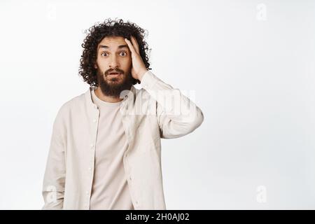 Bild von überrascht arabischen Kerl Blick auf die Kamera verwirrt, kratzen Kopf mit verwirrt Gesichtsausdruck, weißer Hintergrund Stockfoto