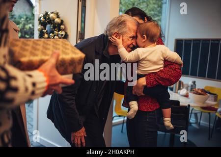 Familie kommt zu Weihnachtsfeierlichkeiten. Ein älterer Mann begrüßte seinen Enkel am Eingang. Stockfoto