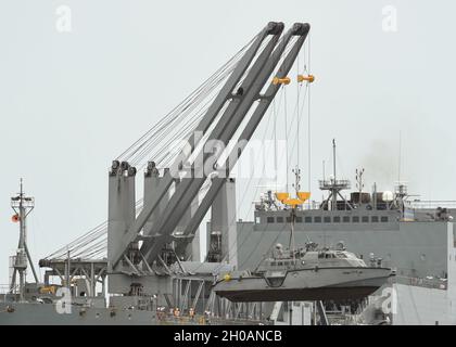 APRA HARBOUR, Guam (Jan 12, 2021) Seeleute, die von der Marine Expeditionary Logistics Capability der Task Force 75 eingesetzt wurden, bedienen einen Doppelkran, um auf einem Mark VI-Patrouillenboot an Bord des großen, mittelschnellen Roll-on/Roll-off-Schiffes USNS Soderman (TA-AKR 317) des Military Sealift Command in Apta Harbour, Guam zu heben. Das Navy Cargo Handling Bataillon 1 ist das einzige aktive Frachtabfertigungsbataillon der Marine und eine schnell einsetzbare Einsatzeinheit des Navy Expeditionary Combat Command, die Schiffe und Flugzeuge unter allen klimatischen und bedrohlichen Bedingungen laden und entladen kann. Stockfoto