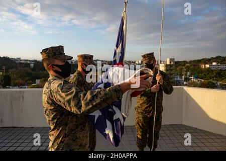 US-Marineinfanteristen befestigen die amerikanische Flagge an einem Fahnenmast auf Camp Foster, Okinawa, Japan, 13. Januar 2021. Die Marineinfanteristen erfüllten ihre täglichen Pflichten, eine feierliche Fahne an der Seite der japanischen Sicherheitsgarde zu führen. Eine tägliche Farbzeremonie mit der Gastgebernation symbolisiert die Zusammenarbeit und die gemeinsamen Anstrengungen der amerikanischen und japanischen Streitkräfte in ganz Japan. . Stockfoto