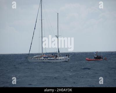 Das Cutter-Boot der Küstenwache Heriberto Hernandez über dem Horizont IV leistet Hilfe für das behinderte Segelschiff Wahu am 14. Januar 2021, etwa neun Seemeilen westlich von Cabo Rojo, Puerto Rico. Die Küstenwache beendete später die Reise für das Schiff Wahu, nachdem es nach der Suche und dem Rettungsboarding des Schiffes mehrere Sicherheitsverletzungen aufgedeckt hatte. Die Wahu war mit zwei Personen an Bord von Florida nach Barbados, als sie angeblich behindert wurde. Sobald der Betreiber des Schiffs Wahu die Reparaturen abgeschlossen und die genannten Verstöße korrigiert hat, wird das Schiff A sein Stockfoto