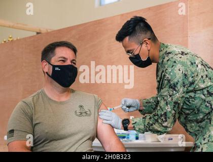 210115-N-BR087-1013 AGANA HEIGHTS, GUAM (JAN 15, 2021) Kapitän Gareth Healy, Kommandeur der Marine Expeditionary Forces Command Pacific-Task Force 75, erhält den COVID-19-Impfstoff vom Hospitalmann Jovoani Lucas mit dem U.S. Naval Hospital Guam. CTF 75-Seeleute nahmen an der freiwilligen Impfung zur Unterstützung der Prioritäten des Verteidigungsministeriums Teil, die darauf abzielen, das amerikanische Volk zu schützen, die Bereitschaft aufrechtzuerhalten und die nationale COVID-19-Reaktion zu unterstützen. CTF 75 ist die primäre Expeditions-Task Force der 7. US-Flotte und ist für die Planung und Durchführung von maritimen Sicherheitsoperationen verantwortlich, erklärt Stockfoto