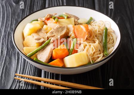 Köstliche hausgemachte japanische Küche Nikujaga Fleisch und Kartoffeln Eintopf aus nächster Nähe in Schüssel auf dem Holztisch. Horizontal Stockfoto