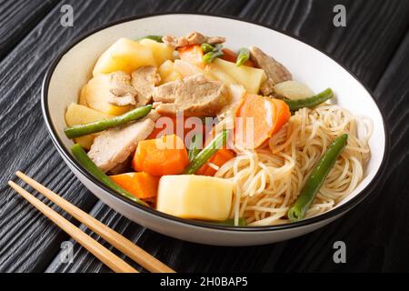 Japanisches Fleisch und Kartoffel Eintopf Nikujaga aus nächster Nähe in einer Schüssel auf dem Holztisch. Horizontal Stockfoto