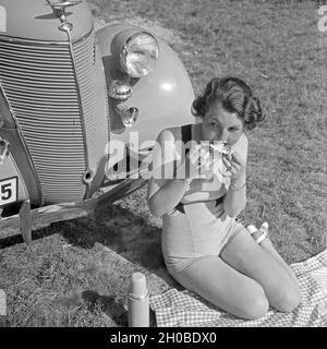 Eine Frau Beim Picknick Vor Einem Ford V6, 1930er Jahre Deutschland. Eine junge Frau, die einen Picknick vor der ein Ford V8, Deutschland der 1930er Jahre. Stockfoto