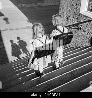 Zwei Mädchen Mit Ihren Schulranzen Auf Einer Treppe Auf Dem Weg Zur Schule, 1930er Jahre Deutschland. Zwei Mädchen mit ihren Schulranzen auf dem Weg zur Schule, Deutschland der 1930er Jahre. Stockfoto