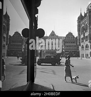 Eine junge Frau spaziert mit ihrem Foxterrier über den Markt in Stuttgart, Deutschland, 1930er Jahre. Eine junge Frau walkingh ihr Fox Terrier Welpe auf dem Markt in Stuttgart, Deutschland 1930. Stockfoto