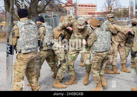 Mitglieder des 629. Militärgeheimdienstbataillons der Nationalgarde der Armee von Maryland versuchen, einen Hausfriedensbruch zu unterlassen, der während des zivilen Störungstrainings am 18. Januar 2021 in Annapolis, Maryland, die richtige Verwendung von Schutzschilden lernt. Die Soldaten stehen bereit, um bei Bedarf der Maryland State Police zu helfen. Stockfoto