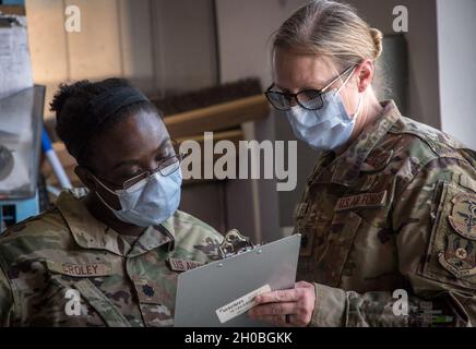 Zwei Luftwaffe der 379. Expeditionary Medical Group untersuchen während der ersten Verteilungsphase des COVID-19-Impfstoffs, der von Mitgliedern der 379. EMDG an priorisierte Mitarbeiter der Al Udeid Air Base, Katar, am 18. Januar 2021 zur Verteilung eintraf. Nach den Freigaungsphasen des Verteidigungsministeriums waren diejenigen, die sie zuerst erhielten, dem Risiko ausgesetzt, täglich ausgesetzt zu werden, wie z. B. medizinisches Personal, Rettungsdienste und öffentliche Sicherheit. Stockfoto