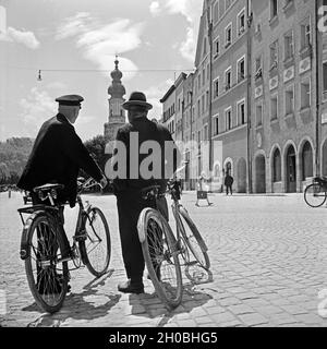 Zwei Männer Mit Ihren Fahrrädern Auf Einem Platz in Burghausen Mit der Kirche St. Jakob Im Hintergrund, 1930er Jahre Deutschland. Zwei Männer mit ihren Fahrrädern auf einem Platz im Zentrum Stadt Burghausen mit St.-Jakobs Kirche im Hintergrund, Deutschland der 1930er Jahre. Stockfoto