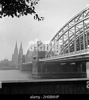 Blick von Deutz auf die Hohenzollernbrücke, den Rhein und den Hohen Dom zu Köln, Deutschland 1930er Jahre. Blick von Deutz auf die Hohenzollern-Eisenbahnbrücke und den Kölner Dom, Deutschland 1930er Jahre. Stockfoto